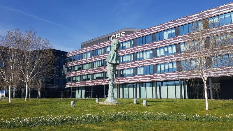 Het kantoor van het Centraal Bureau voor de Statistiek in Heerlen, met een beeld op het gazon ervoor.