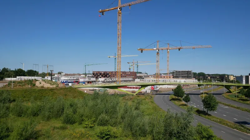 Bouwwerkzaamheden in nieuwbouwgebied Hof van Holland in Nijmegen-Noord, gezien vanaf station Nijmegen Lent, met bouwkranen.